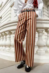 Pantalón de tiro alto y pernera recta con estampado de rayas verticales en tonos azul, marrón y beige. Incluye un cinturón delgado de color marrón oscuro con hebilla metálica dorada.