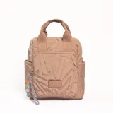 Mochila de diseño acolchado en color beige, con compartimento principal y bolsillo frontal con cierre. Presenta asas superiores de mano y correas ajustables, con un detalle de llavero colgante con cuentas decorativas.