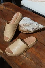 Sandalias chatas color beige con capellada con textura símil piel de reptil y suela de goma.