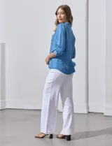 Camisa celeste de lyocell, con cuello a la base, escote en V y abertura central con botones. Tiene bolsillos aplicados en la parte delantera y mangas 3/4 regulables con presilla y botón.