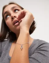 Dije charm de aleación de metales bañados en plata de ley con forma de cruz.