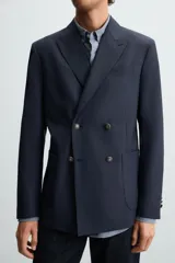 Blazer regular fit color azul marino, confeccionada en tejido con lana. Presenta cuello con solapas de pico, manga larga con puño abotonado, bolsillos de vivo en el pecho y de plastrón en la cadera. Incluye un bolsillo interior y aberturas en la espalda. El cierre es frontal con botonadura cruzada.