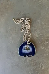 Collar de cadena de eslabones plateados con un gran dije colgante de piedra ágata natural en tonos azules.