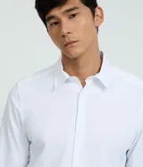 Camisa de manga larga color celeste, corte slim fit, con cuello inglés y cierre frontal de botones.