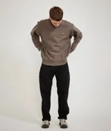 Buzo de cuello redondo Carhartt, confeccionado en tejido de algodón de alta calidad. Presenta un corte holgado, puños y ruedo acanalados, y el logo de la marca bordado en el pecho.