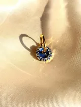 Aro individual dorado con dije circular azul con strass blancos.