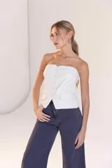 Top strapless blanco con corte tipo chaleco, cierre frontal con botones y bolsillos simulados.