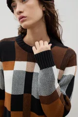 Sweater de punto con diseño jacquard a cuadros en tonos azul, marrón, crema y negro. Presenta cuello redondo, puños y ruedo acanalados, con un corte holgado y cómodo.