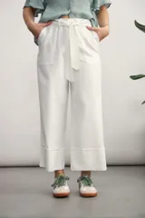 Pantalón de corte recto y tiro alto, color blanco, con cintura elástica y lazo ajustable del mismo tejido. Presenta bolsillos laterales y dobladillo ancho en la parte inferior.