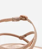 Sandalia plana color dorado con acabado metalizado, diseño de tiras finas, algunas de ellas con incrustaciones de brillo, y cierre ajustable con hebilla al tobillo.