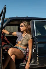 Top corto de diseño asimétrico con escote cruzado y mangas cortas, confeccionado en tela con estampado geométrico multicolor en tonos azul, verde y ocre.