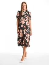 Vestido midi de satén con estampado floral sobre fondo negro. Presenta cuello a la base con frunce, mangas cortas abullonadas con terminación elástica, cintura definida y un tajo lateral pronunciado. Incluye forro interno y lazo posterior para ajustar el cuello.