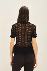 Camisa liviana negra tejida en punto desagujado con cuello en rib y cartera con botones símil nacar en el delantero.