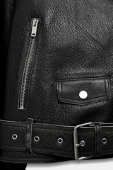 Chaqueta tipo biker de piel negra con solapas, cierre frontal asimétrico con cremallera, bolsillos con cierre y cinturón ajustable con hebilla metálica en la cintura.