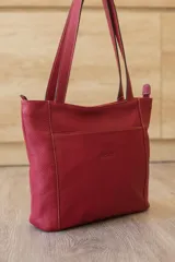 Cartera tipo tote de cuero vacuno negro con doble asa de hombro, panel superior liso y bolsillo exterior frontal con textura símil cocodrilo y costuras visibles en contraste.