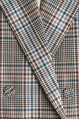 Blazer cruzado de sarga de algodón con estampado a cuadros en tonos beige, azul y marrón. Presenta solapas de pico, botones forrados, hombreras, un bolsillo superior insertado y dos bolsillos ribeteados con solapa. Las mangas tienen botones de cascada en los puños y cuenta con una abertura doble en la parte trasera.