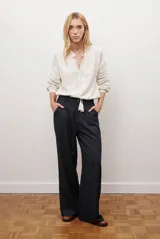 Pantalon de corte recto y pierna ancha, confeccionado en tejido tipo denim oscuro. Presenta tiro alto, cintura con cierre frontal y bolsillos laterales funcionales.