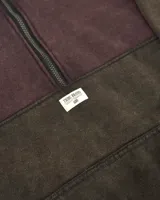 Buzo de corte oversized con medio cierre frontal, confeccionado en una combinación de colores violeta en la parte superior y negro en la parte inferior. Presenta cuello alto, puños y ruedo acanalados, y un bolsillo tipo canguro frontal con etiqueta de la marca.