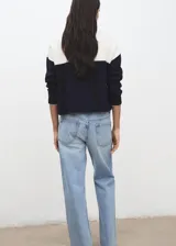 Jersey de punto de manga larga, con diseño bicolor en blanco y negro, cuello alto con cierre de cremallera corta.