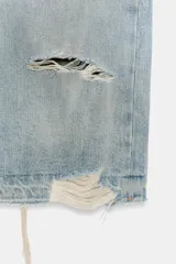 Falda midi de denim en tono azul claro, con diseño de cinco bolsillos, tiro medio y detalles de roturas. Presenta cierre frontal con cremallera y botón metálico, con bajo deshilachado y abertura en la espalda.