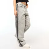 Pantalón de jean gris con lavado ácido y corte holgado. Presenta una franja vertical negra a lo largo de la pierna.