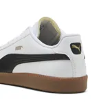 Championes Puma 9-T de estilo urbano, con capellada blanca de cuero sintético, franja lateral negra, puntera de gamuza en tono beige y suela de goma color caramelo.