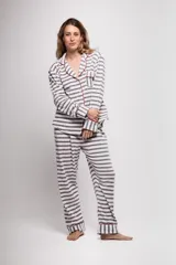 Pijama de tela tipo velvet a rayas horizontales grises y blancas, con vivos en color rojo. Incluye camisa de manga larga con botones frontales y bolsillo en el pecho, y pantalón recto con elástico en la cintura.