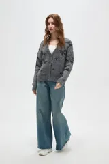 Cardigan de punto gris con estampado de estrellas negras, cuello en V, cierre frontal con botones y mangas largas con puños acanalados.