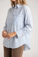 Camisa oversize de manga larga con diseño de rayas verticales verdes y blancas, confeccionada en mezcla de viscosa y lino. Presenta cuello camisero, cierre frontal con botones, puños abotonados y un bolsillo aplicado en el pecho.