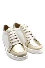 Zapatillas deportivas de cuero, combinando paneles en color blanco y detalles metalizados en tono dorado. Presentan cierre mediante cordones blancos y suela de goma plana.
