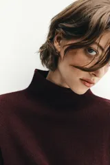 Jersey de punto color bordó con cuello subido, manga larga y diseño de corte holgado con costuras caídas en los hombros.