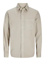 Camisa de manga larga color beige, con cuello clásico, cierre con botones y bolsillo en el pecho. Corte recto.