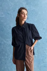 Camisa de jean azul oscuro con calce relajado, cuello clásico, bolsillo aplicado en el delantero y mangas largas abullonadas con puños abotonados.