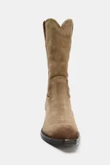 Botín estilo cowboy confeccionado en serraje color marrón, con tacón medio en bloque, punta fina y detalle de pespuntes decorativos en la parte frontal.