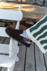 Zuecos de cuero marrón con talón descubierto y suela de goma.