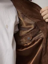 Campera biker de cuero color marrón, con cuello mao, cierre frontal metálico, bolsillo en el pecho con cierre y bolsillos laterales.