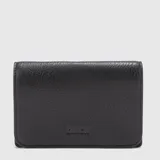 Tabaquera de cuero negro con diseño rectangular, cierre plegable y logo grabado en la parte inferior frontal. Cuenta con compartimento interno para tabaco, bolsillo con cierre para filtros y dispensador de papelillos.