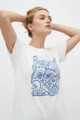 Remera de manga corta color azul con estampa frontal oscura de una ballena decorada con motivos florales.