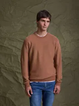 Sweater de punto color camel, con cuello redondo y mangas largas con puños acanalados.