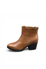 Bota tipo Chelsea color marrón, con taco cuadrado y suela negra. Presenta elástico lateral con costuras pespuntadas visibles y diseño clásico.