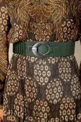 Cinto ancho de cuero color verde oscuro con secciones elásticas en la parte trasera y una hebilla metálica ovalada plateada. El diseño es ceñido a la cintura.