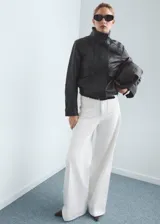 Jeans blancos de corte wide leg y tiro alto, con bolsillos de parche delanteros y trabillas para cinturón.
