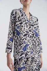 Pijama de camisa y pantalón con estampado floral en tonos azul, blanco y negro. Camisa de mangas largas con detalle de vivos a contratono en lurex plateado en el cuello y en las mangas.