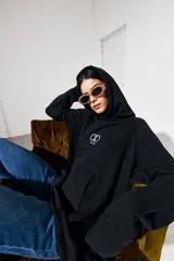 Canguro negro oversize de algodón con capucha y bolsillo delantero tipo canguro. Logo bordado en el pecho.