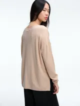 Sweater de punto amplio con sutiles micro lentejuelas integradas al tejido. Presenta cuello redondo relajado, hombros caídos y mangas largas con puños ajustados. Su diseño cuenta con un largo generoso y aberturas laterales en el ruedo.