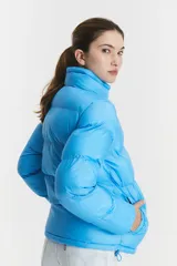 Campera puffer acolchada de color azul brillante, con cuello alto y cierre frontal mediante botones a presión. Diseño de corte estándar con costuras horizontales.