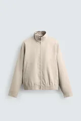 Cazadora regular fit de algodón color beige, con cuello subido, cierre frontal de cremallera y bolsillos laterales de vivo.