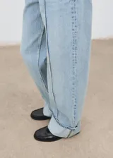 Jeans de tiro medio con diseño de corte recto y largo. Presentan bajo con dobladillo vuelto, cinco bolsillos, cierre de botón y cremallera, y detalle de costuras verticales a lo largo de las piernas.
