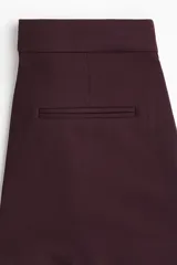 Pantalón de vestir color borgoña oscuro, de corte bootcut con raya marcada en el frente y la espalda. Presenta pretina prolongada con cierre oculto y bolsillos al bies y ribeteados en la parte trasera.