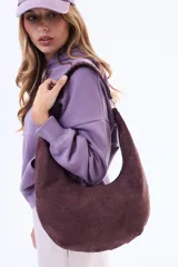 Cartera tipo hobo de diseño curvo, confeccionada en material símil gamuza con textura trenzada. Cuenta con una correa integrada al cuerpo del bolso y cierre superior.